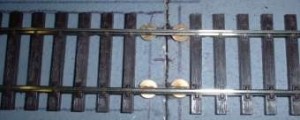 Rail soldered to brass screws at the baseboard edge